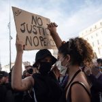 protesters hold up "no justice no peace" sign